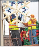 FIRST SNOWFLAKES OF THE  SEASON: A Charles City crew puts up Christmas decorations  Thursday on N. Main Street.